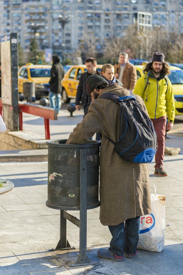 homeless man digging in trash can